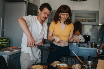 A couple of friends enjoying cooking pasta in a modern kitchen setting. The atmosphere is relaxed and joyful, emphasizing friendship and culinary enjoyment.