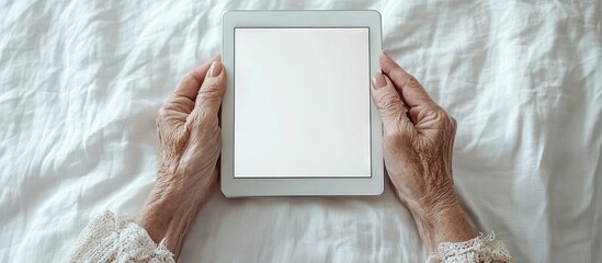 Elderly woman using a digital tablet to showcase something on the screen set against a light background Template copy space mock up Technology for seniors concept Aged wrinkled hands holding the ta