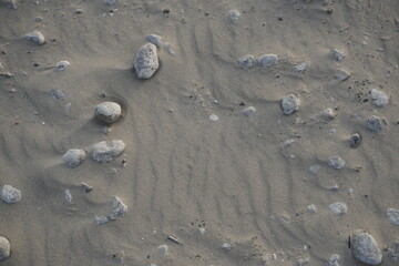 Top view of sand on the beach. Shadows from stones and surface relief. Texture underfoot.