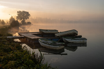 Jesienny mglisty poranek nad stawem z łódkami i molem. © Elżbieta Kaps