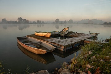 Jesienny mglisty poranek nad stawem z łódkami i molem. © Elżbieta Kaps