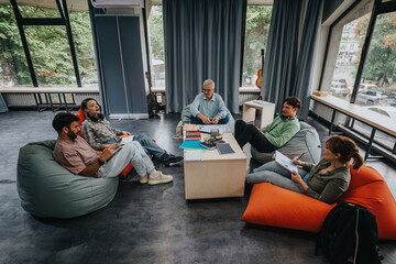 A group of diverse students collaborating with their professor in a contemporary lounge. The...