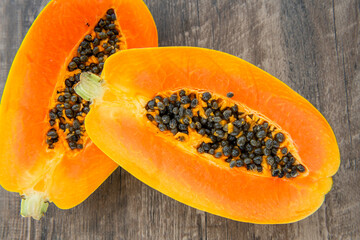 Papaya fruit on a dark wooden background. Slices of sweet papaya, Halved papayas