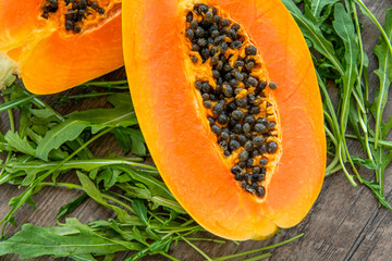 Papaya fruit and rucola on a dark wooden background. Slices of sweet papaya and rucola