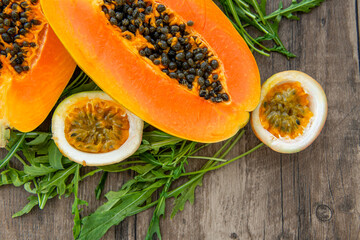 Papaya fruit passion fruit and rucola on a dark wooden background