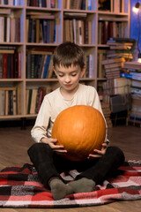 Fototapeta premium Young boy with pumpkins in a library, creating a cozy fall atmosphere. Perfect for seasonal content.