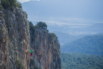 A tightrope walker walks along a cable stretched over a canyon.