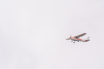 Small ultralight airplane with overhead wing and single propeller flying in sunset sky.