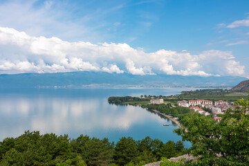 Breathtaking panoramic view of Lake Ohrid, a UNESCO World Heritage site in North Macedonia. Summer vacation in charming lakeside town. Cloud covered mountains are reflected on the calm water surface