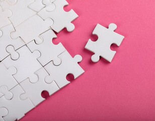 Image of white puzzle pieces scattered on a pink background