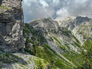 Scenic hiking trail surrounded by majestic steep mountain ridges of Albanian Alps (Accursed Mountains). Crossing high altitude pass between Valbone Valley and Thethi National Park, Albania. Wanderlust