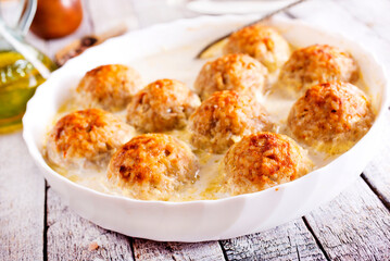 Baked chicken balls, meat balls with white sauce and cheese