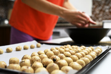 Young woman making cookies for her children in her kitchen at home