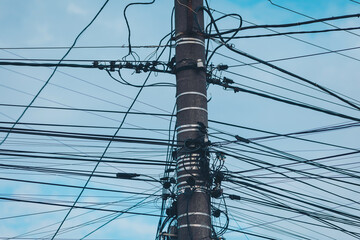 Electric Poles and Cables and set against a bright blue sky. Electric pole with messy wire. 