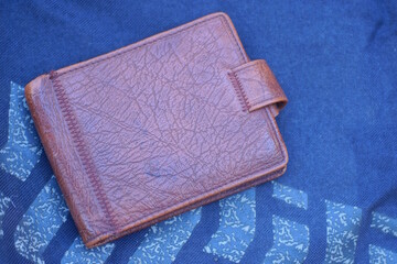 one old closed brown leather wallet lies on a black gray table