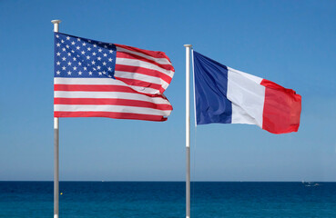 The national flags of the United States and France next to the ocean on a sunny day