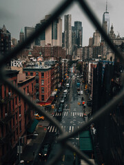 View through fence of urban street with buildings and city skyline in background