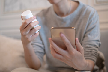 Adults holding vitamin medicine using smartphone mobile phone searching reading looking drug...
