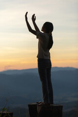 Fototapeta premium Girl praying to God on the mountain sunset background.