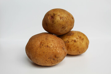 Fototapeta premium Three potatoes unpeeled, isolated on white background