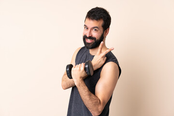 Caucasian sport man with beard making weightlifting over isolated background smiling and showing victory sign