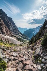 Obraz premium Mountain range with a valley in between. The sky is blue and the sun is shining. The mountains are covered in trees and the valley is rocky