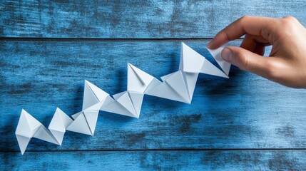Creative Hand with Paper Origami Figures on a Wooden Background