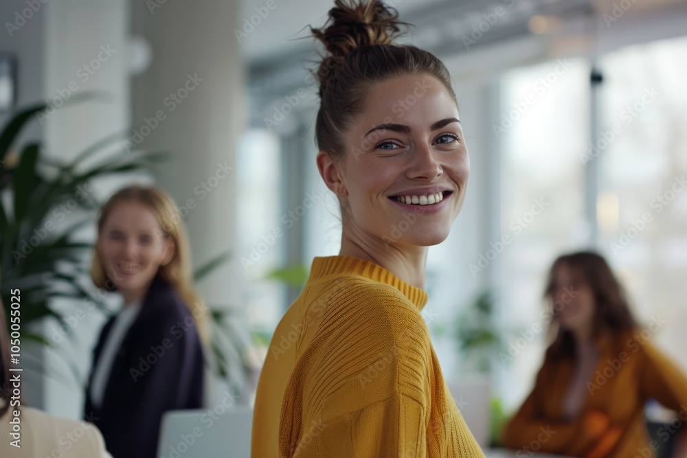 Wall mural a cheerful woman smiling warmly in a relaxed office environment, with colleagues visible in the back