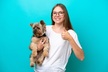 Obraz premium Young Lithuanian woman holding a dog isolated on blue background with thumbs up because something good has happened