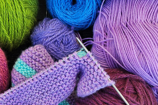 A knitting in progress, surrounded by vibrant threads and essential tools. The concept of crafting, DIY, or textile themes.