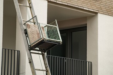 Furniture lift transporting boxes on building facade: moving and relocation service