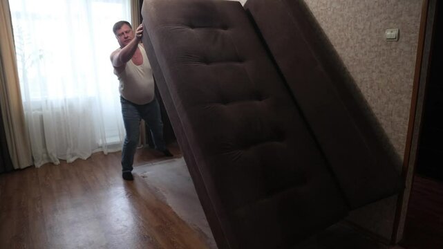 man lifts sofa infested with bed bugs and house parasites for treatment.