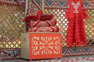 Interior of a traditional nomadic dwelling a yurt - a chest, pillows and blankets, felt carpets,...