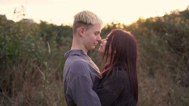      A 15-year-old teenage couple in love hugs and kisses at sunset