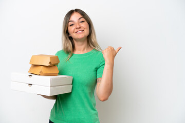 Fototapeta premium Young Rumanian woman holding fast-food isolated on white background pointing to the side to present a product