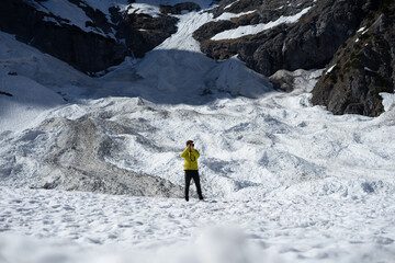 Person standing on a snowy landscape surrounded by mountains.