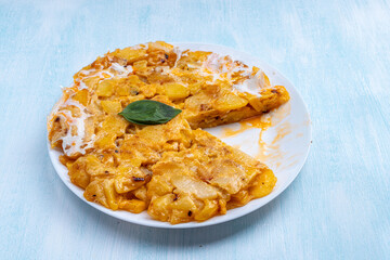 Spanish omelette (Tortilla de patatas) with potatoes and onions, on a plate, one piece cut off. Typical Spanish cuisine.