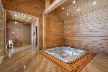 A large bathtub with hydro massage in a spacious room of a wooden private house. Entrance to the...