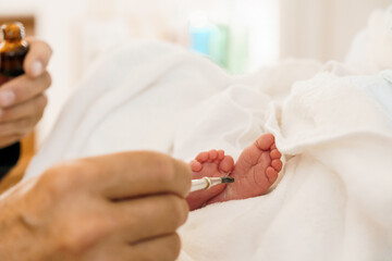 Intimate Care Moment: A Caregiver Applying Ointment to a Newborn's Tiny Feet
