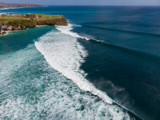 Aerial view of azure waves crashing on a rugged coastline.