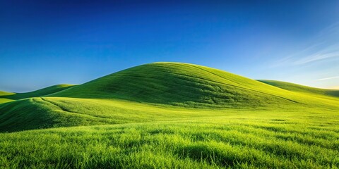 Obraz premium Scenic view of green grassy hill under clear blue sky