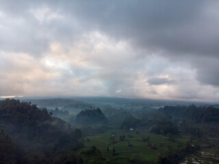 A serene landscape with misty hills under a cloudy sky.