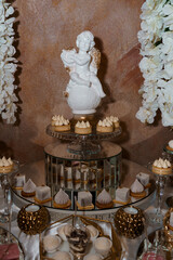 Elegant Dessert Table Featuring a White Angelic Figurine and Exquisite Treats