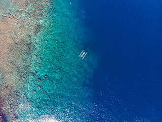 Aerial view of a boat floating over a vibrant coral reef in clear blue waters. © Marcel