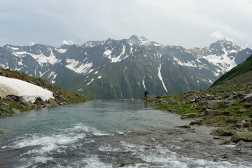 A serene mountain stream flows beneath snow-capped peaks.