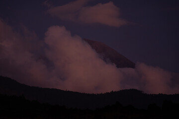 Mountains silhouetted against a dramatic, cloudy evening sky.