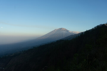 A majestic mountain rises against a clear sky at dawn.