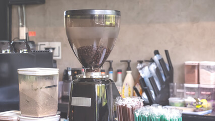 Electric coffee machine and black case with grinder container on counter inside of modern loft...