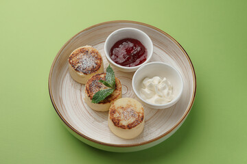 cheesecakes with jam and sour cream on a green background