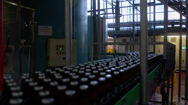 Bottles slowly moving on a conveyor belt in a brewery